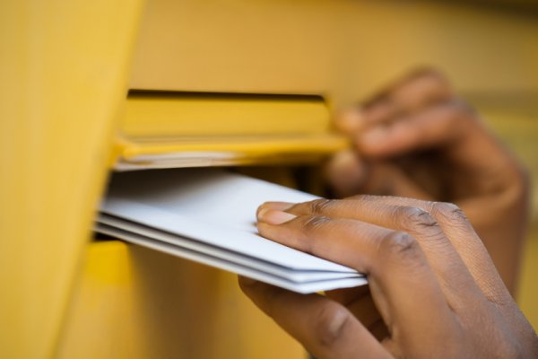 Person putting mails in a mailbox