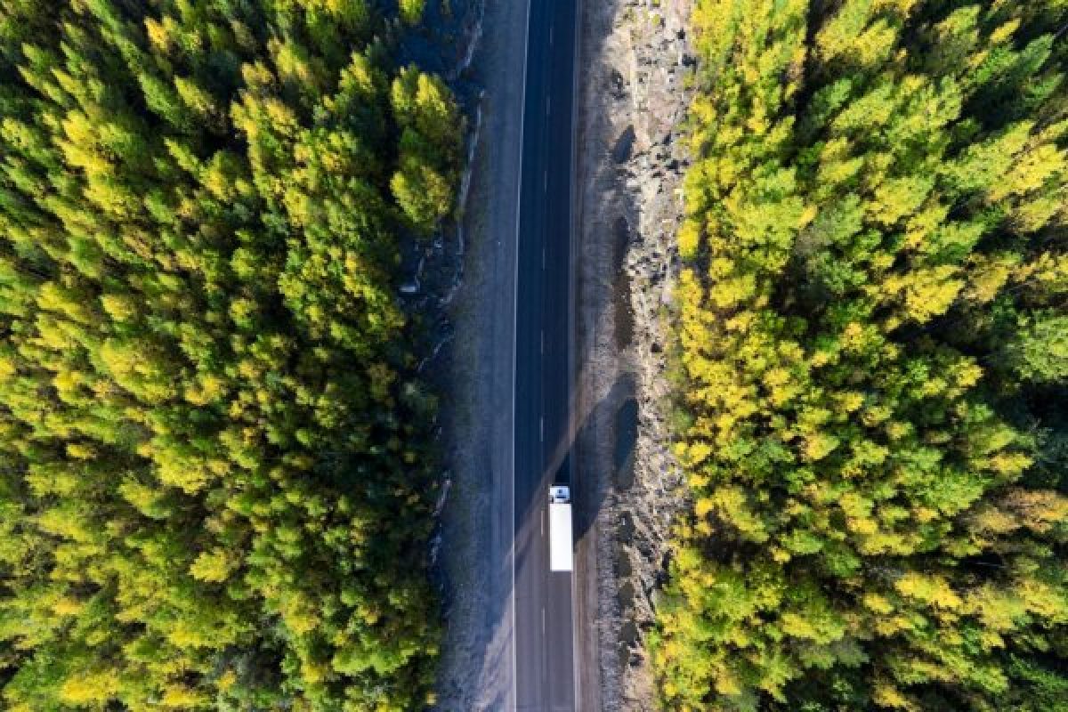 Aerial view of a delivery truck on a road through a forest